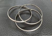 Four sterling silver bangles nested together on leather surface
