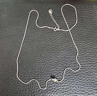 Full view of silver snake chain necklace with sliding bead and extender.