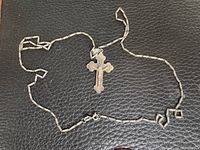 Full view of bar-link chain and crucifix pendant laid flat