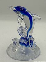 Front view of crystal dolphin figurine showing clear and blue coloration and wave base