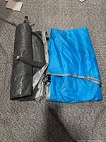 Rolled blue and grey tent components laid out