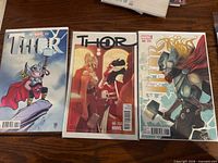 Front view of three bagged Thor variant comics on table