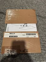 Packaged IKEA Billy glass shelf showing label, dimensions and hardware