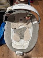 Front view of Ingenuity baby lounge seat showing bear insert, control panel and canopy with hanging toy