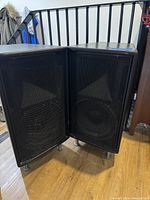 Both speakers standing side by side showing grilles and metal legs