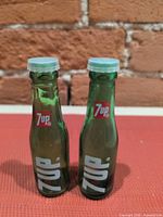 Front view of both green glass 7Up bottle shakers showing logos