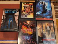 Five DVD cases: Sleuth, John Wayne Chisum, The Saint, Bowfire, The Interpreter