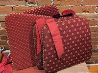 Four burgundy reversible chair cushions showing both patterns and tie straps
