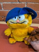 Front view of Garfield plush wearing blue cap