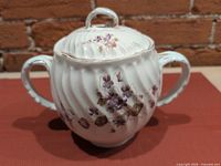 Front view of covered sugar bowl showing floral pattern, handles and finial