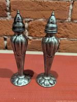 Front view of both tarnished silverplate shakers