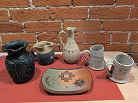 All six ceramic pieces on table against brick wall