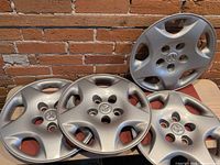 All four matching Dodge hubcaps displayed against brick wall