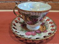 cup on saucer showing overall design, gold rim, pear artwork
