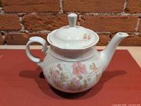 teapot front view showing floral design, spout, handle and lid