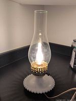 Lamp lit showing base, chimney and cord