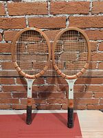 Front view of both wooden tennis rackets showing complete frames, strings, and grips