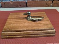Closed box showing brass duck on lid, front edge wear visible