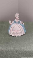 Front view of ceramic Rococo lady figurine showing color scheme, fan, gown details