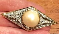 Front view of diamond-shaped brooch showing pearl and rhinestones