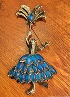 Front view showing entire brooch with blue rhinestone skirt and umbrella