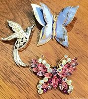 Group shot of three brooches on wood surface
