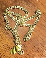 Full view of gold plated curb/Cuban link necklace coiled on wood surface showing overall design