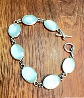 Full view of bracelet laid flat showing seven blue mother-of-pearl links and clasp