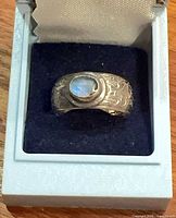 Ring in box showing moonstone cabochon and floral band
