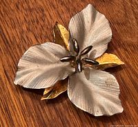 Front view of sterling silver trillium brooch showing brushed petals, gold leaves, and stamen