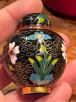 Front view of cloisonné snuff bottle showing floral design and brass base