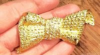 Front view of gold plated bow brooch showing textured finish and rhinestone center