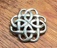 Front view of sterling silver Celtic knot brooch on wood surface