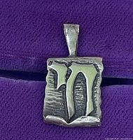Front view of pendant showing raised Chai symbol and antiqued scroll texture