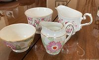 Four china pieces: two creamers, two sugar bowls