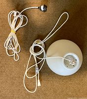 Two pendant lamps with cords and ceiling fittings on carpet