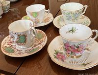 Four assorted vintage bone china cup and saucer sets on table