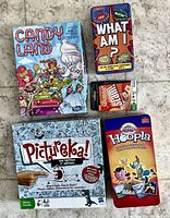 All five game boxes/tins: Candy Land, What Am I?, Scrabble Slam, Pictureka!, Hoopla