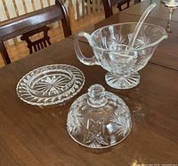 Gravy boat with ladle and butter dish parts on table
