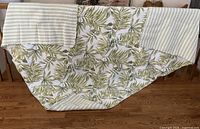Quilt draped over railing showing leaf side, striped reverse, and two pillow shams