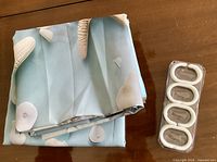 Folded seashell print curtain with package of hooks