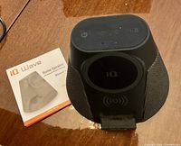iQ Wave speaker front with IQ logo and Qi cradle, instruction pamphlet