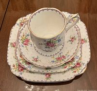 Stacked view of teacup on three matching plates showing pattern and condition