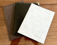 Three faux-leather portfolios closed