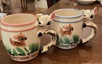 Front view of both mugs showing deer handles, painted fawns, lettering