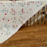 Full view of hand-quilted patchwork quilt draped over railing showing pattern and size