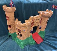 Front three-quarter view of castle showing towers, lion head, drawbridge, flag details