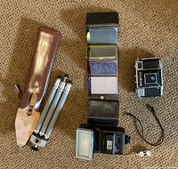 Group shot of camera, tripod, lighting tool, filters, case, cable