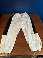 Full view of white Jordan Dri-Fit pants with black side panels laid flat