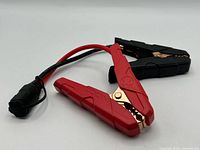 Red and black NOCO jumper clamps attached by cable